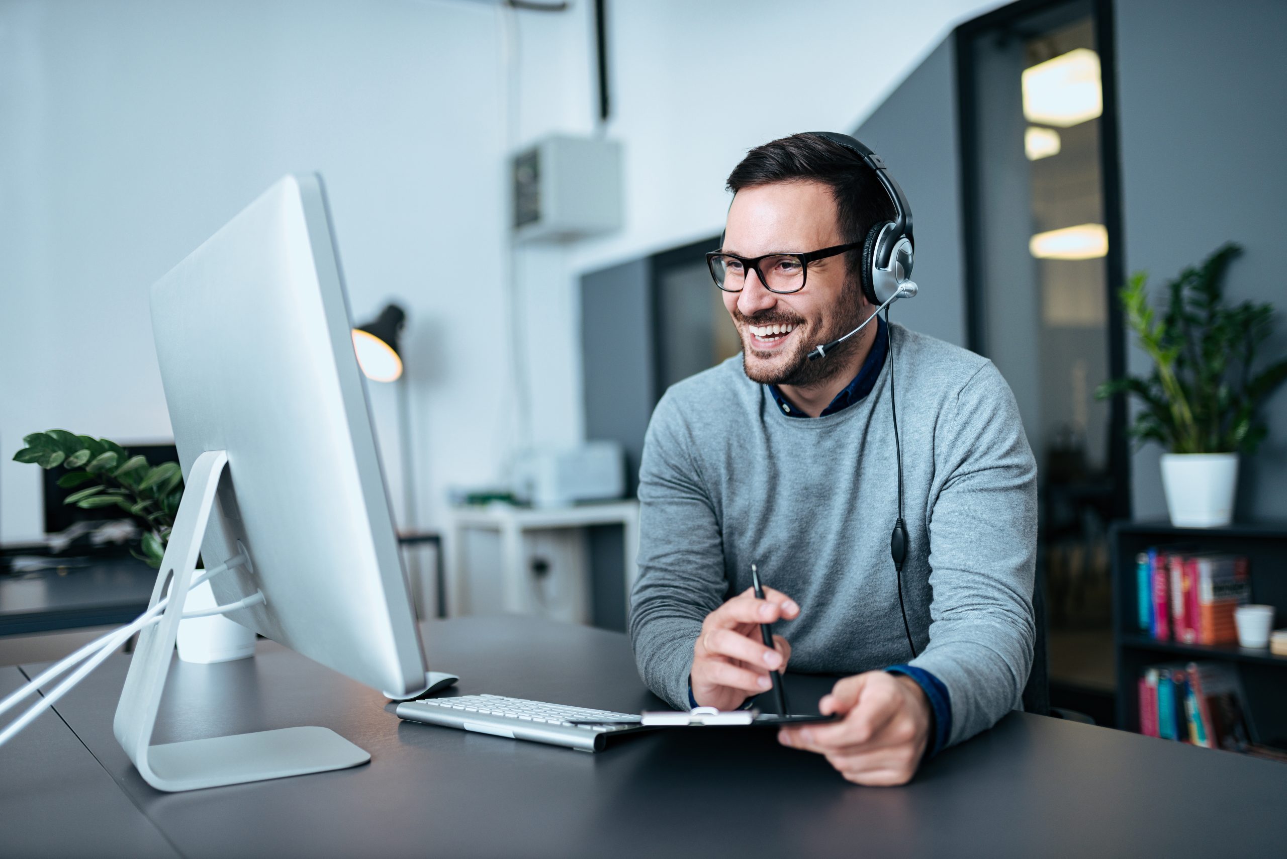 Portrait of a casual smiling businessman using headset when talking to customer.